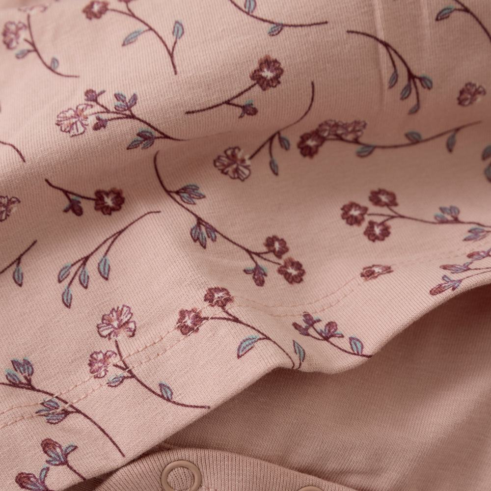 Detailansicht des floralen Musters, der Raffung und des Halsausschnitts am Minymo Bodykleid für Mädchen.