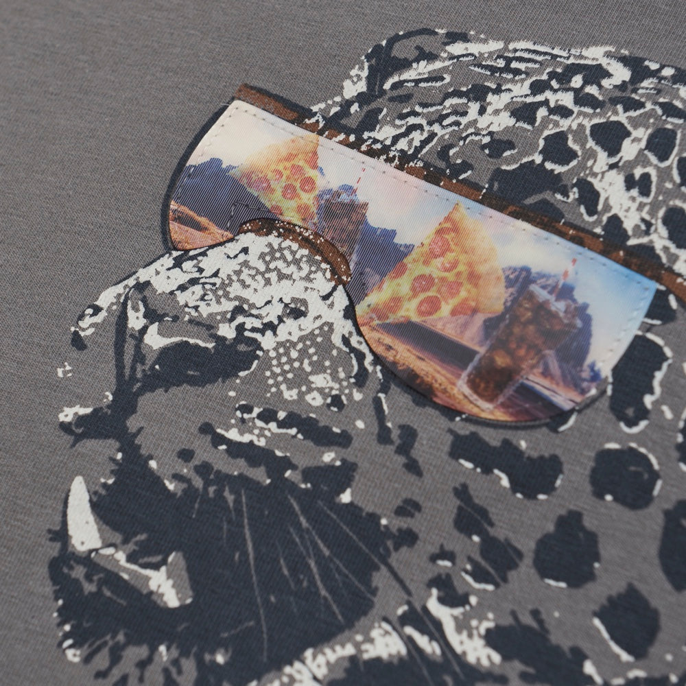 Das T-Shirt hat einen großen Leopardenprint mit Sonnenbrille auf der Vorderseite. Auf dem Aufdruck steht „Cool dude“. Das T-Shirt besteht aus einer weichen Baumwollmischung. Nahaufnahme von Aufdruck