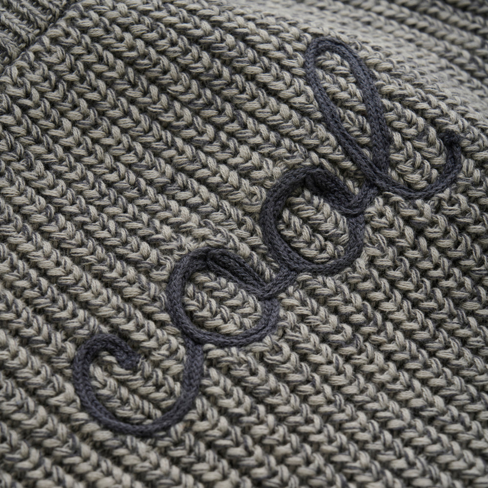 Nahaufnahme des „Cool“-Schriftzuges auf dem grauen Strickpullover von Minymo.