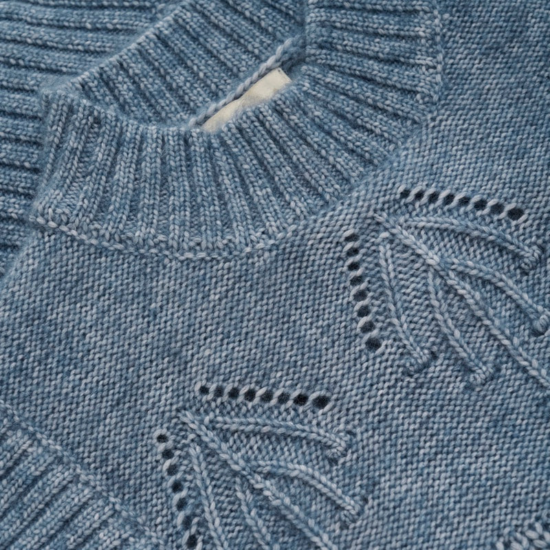 Der Pullunder hat einen Rundhalsausschnitt mit breitem Rippstrickrand. Die Weste verfügt über feine Details wie ein Lochmuster und Doppelstrick; Detailaufnahme Stehkragen und Strickmuster