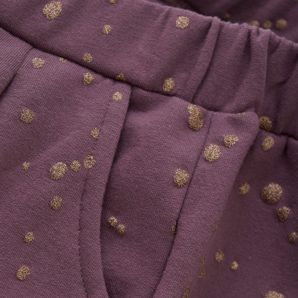 Die Sweatpants von Creamie in violett sind mit goldenen Punkten verziert. Die Hose hat Seitentaschen und ab dem elastischen Bund sind Falten in den Stoff eingenäht. Sie bestehen aus einer schönen Baumwollqualität mit etwas Stretch. Nahaufnahme