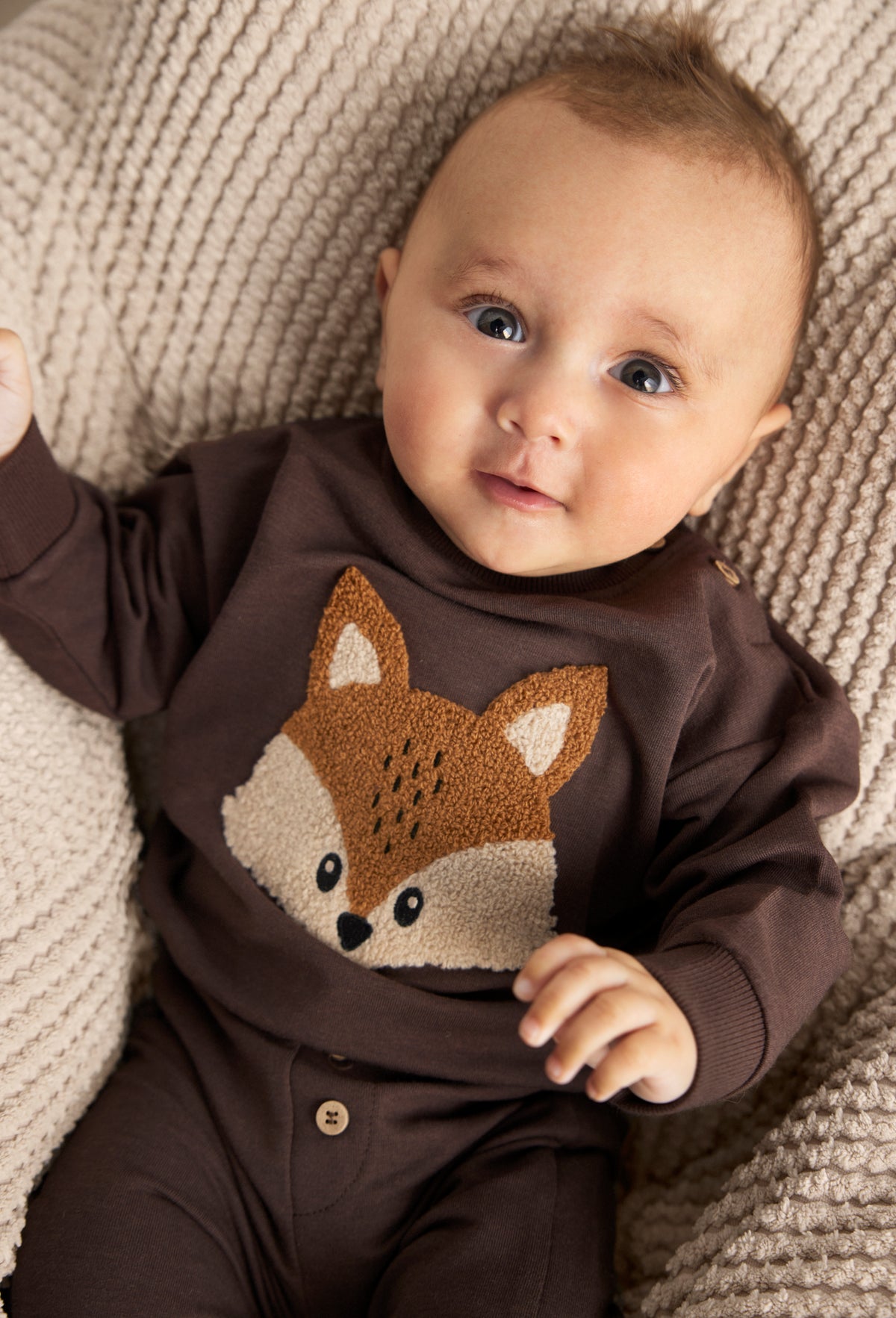 Lifestyle-Bild: Baby trägt Minymo Schweatshirt und Sweatpants mit Fuchsapplikation in dunkelbraun.