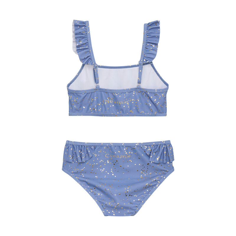 Erhältlich in einem wunderschönen Blau mit goldenen Punkten, ist der Bikini besonders schick. Der Bikini ist vorne und hinten mit Rüschen an den Trägern und an der Taille verziert. Ein perfekter Sommer-Bikini!