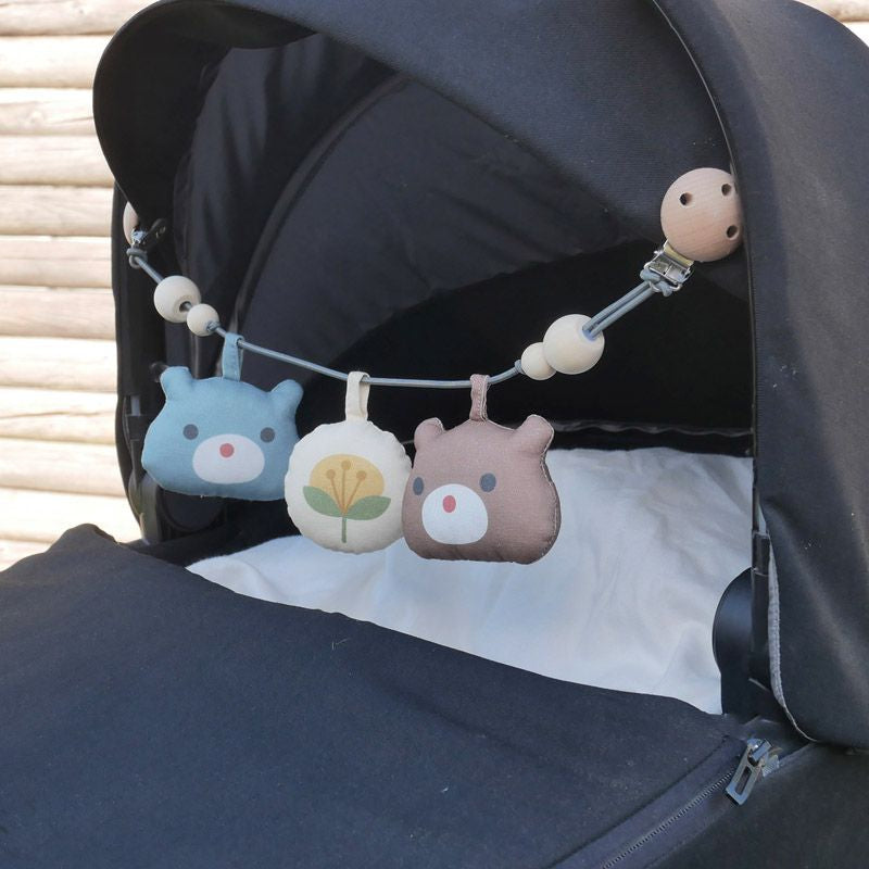 Die Kinderwagenkette Bär Liv mit den 2 Bären und einem Ball regt Babys Sinne an und sorgt für Unterhaltung auf Spaziergängen.