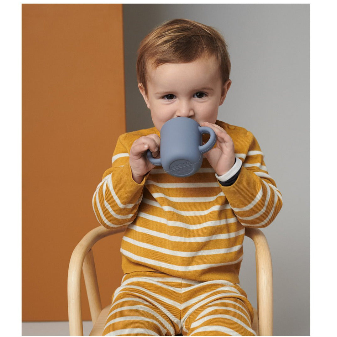 Der Neil Cup ist perfekt, um das Trinken aus Tassen zu lernen. Er hat einen abnehmbaren Deckel mit einem kleinen Auslauf und glatten Griffen. Die Griffe sorgen für einen festen Griff und ermöglichen es dem Kind, das Halten und Kippen zu üben und sich auf die Verwendung einer offenen Tasse vorzubereiten.