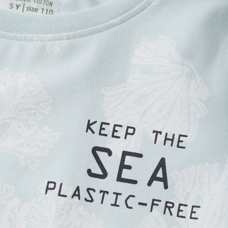 Das Shirt ist unifarben und hat Korallen aufgedruckt. Auf der linken Seite hat es einen Spruch aufgedruckt " Keep the sea plastic free ".